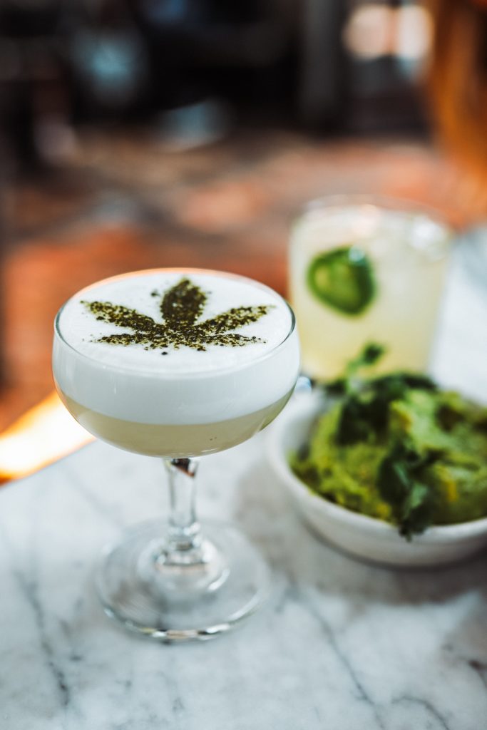 cocktail in a glass with cannabis leaf dusted on top