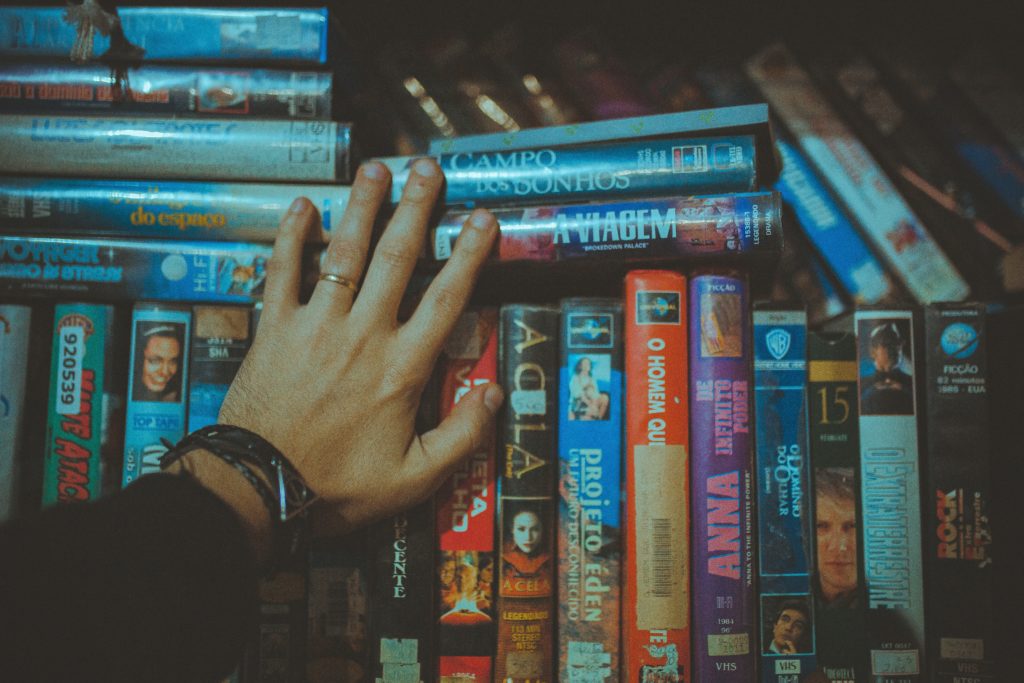 Hand touching a stack of vhs movies stoner movies