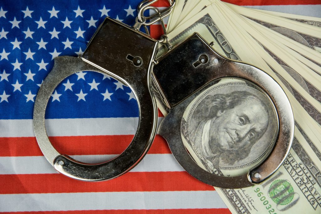 Handcuffs over money and American flag